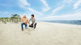 VermögensPlan Premium: Vater und Sohn haben am Strand ein Prozentzeichen in den Sand gemalt.